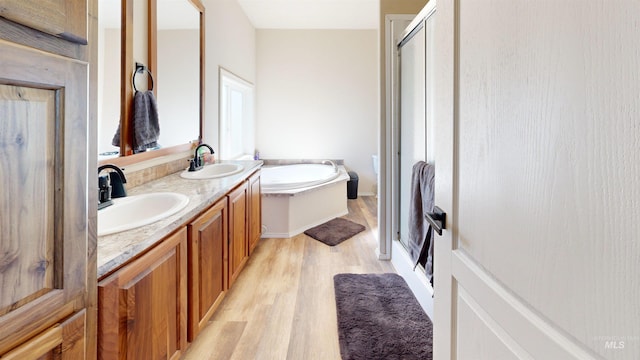 full bath featuring a sink, wood finished floors, a garden tub, and a stall shower