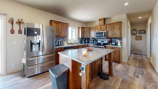 kitchen with backsplash, light countertops, appliances with stainless steel finishes, light wood-style floors, and brown cabinetry