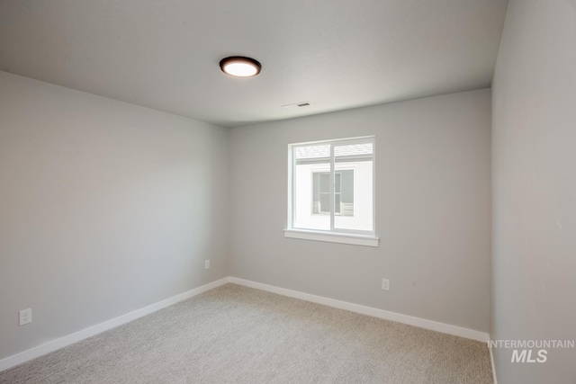 carpeted spare room with visible vents and baseboards