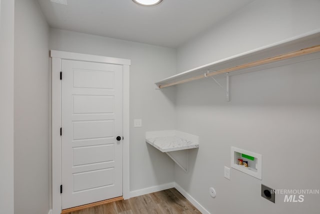 clothes washing area with baseboards, hookup for a washing machine, light wood-style floors, hookup for an electric dryer, and laundry area