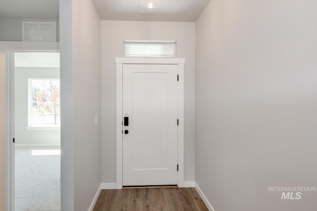 doorway to outside with baseboards, visible vents, and wood finished floors