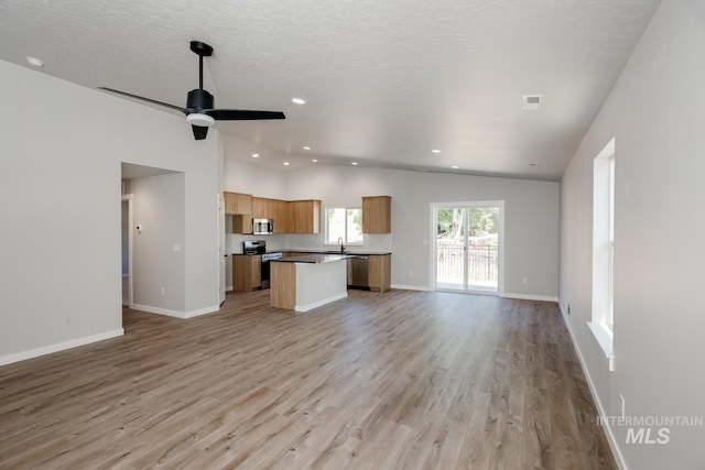 unfurnished living room featuring recessed lighting, light wood-type flooring, vaulted ceiling, and a sink