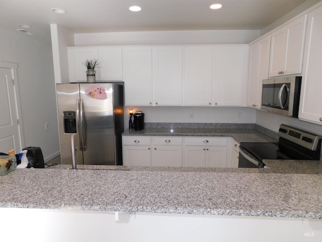 kitchen featuring appliances with stainless steel finishes, white cabinetry, and light stone countertops