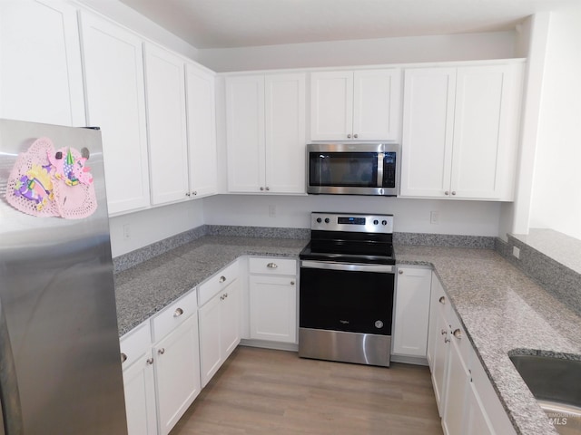 kitchen with white cabinetry, sink, stainless steel appliances, and light hardwood / wood-style floors