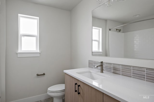 bathroom with vanity, toilet, walk in shower, and tasteful backsplash