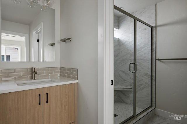 bathroom featuring vanity, walk in shower, and tasteful backsplash