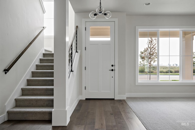 entrance foyer featuring dark wood-type flooring, a healthy amount of sunlight, and a notable chandelier