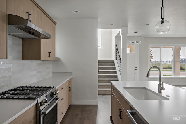 kitchen with appliances with stainless steel finishes, tasteful backsplash, dark wood-type flooring, sink, and pendant lighting