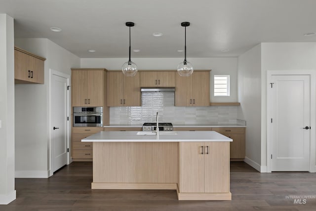 kitchen with decorative light fixtures, an island with sink, dark wood-type flooring, and stainless steel oven