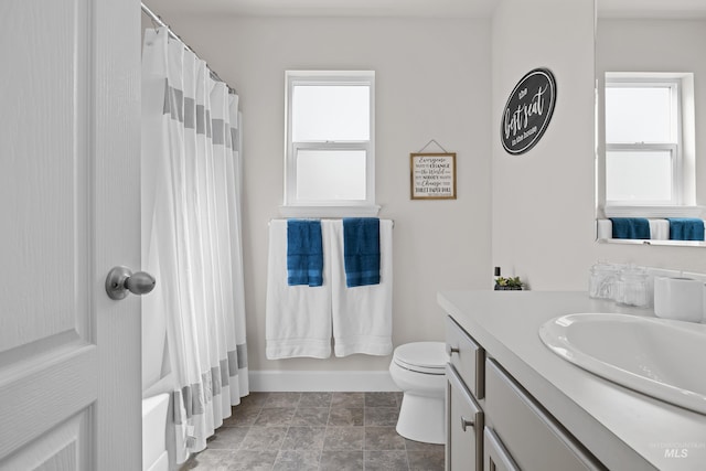 full bathroom featuring plenty of natural light, shower / bath combo with shower curtain, vanity, and toilet