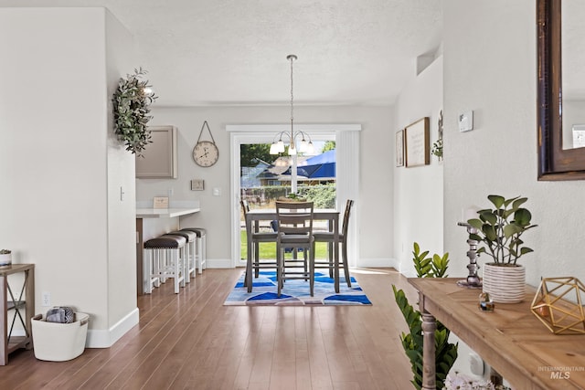 dining area featuring hardwood / wood-style flooring, an inviting chandelier, and a textured ceiling