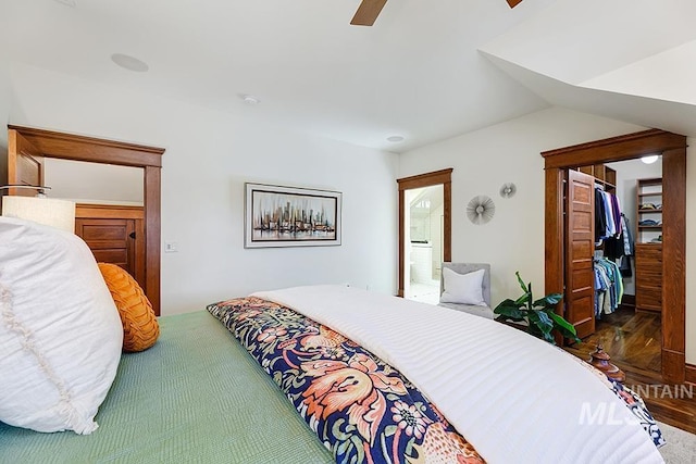 bedroom with vaulted ceiling, ensuite bathroom, wood-type flooring, a walk in closet, and ceiling fan