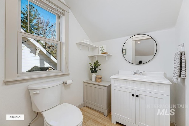 bathroom featuring hardwood / wood-style flooring, vanity, toilet, and vaulted ceiling