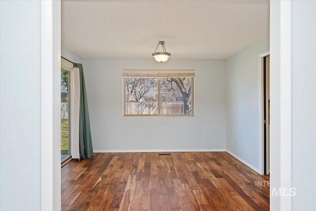 empty room with visible vents, baseboards, and wood finished floors