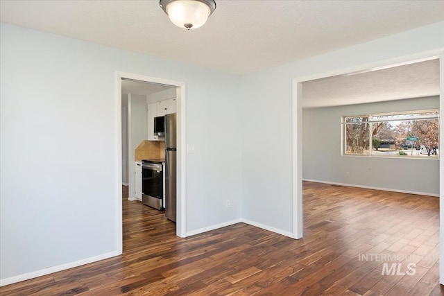 empty room with dark wood-type flooring and baseboards