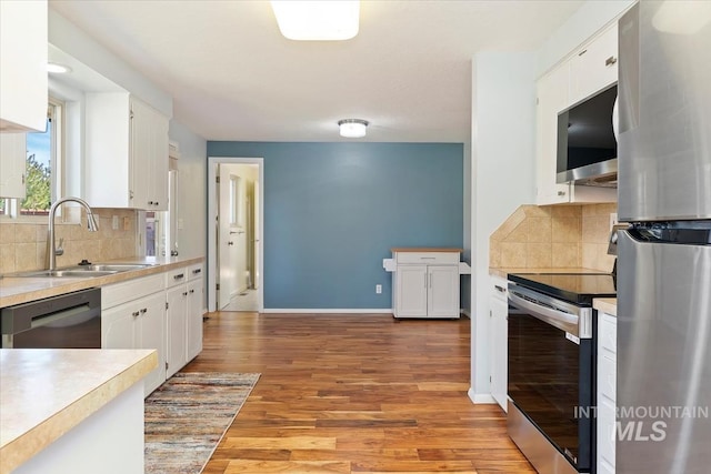 kitchen with white cabinetry, stainless steel appliances, light countertops, and a sink