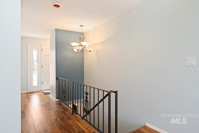 stairs featuring a notable chandelier, wood finished floors, and baseboards