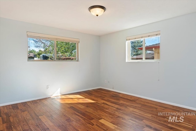 spare room with baseboards and wood finished floors