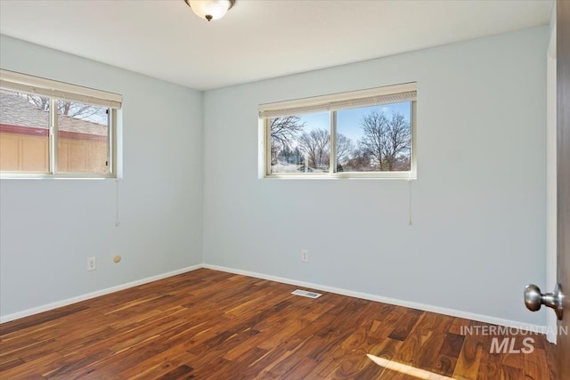 unfurnished room with visible vents, baseboards, and wood finished floors