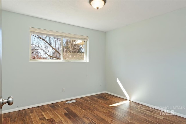 empty room with visible vents, baseboards, and wood finished floors