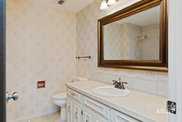 bathroom with visible vents, toilet, vanity, and wallpapered walls