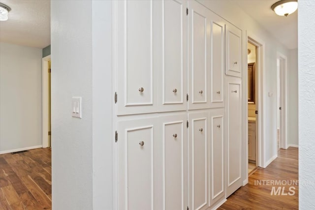 hallway featuring baseboards and wood finished floors