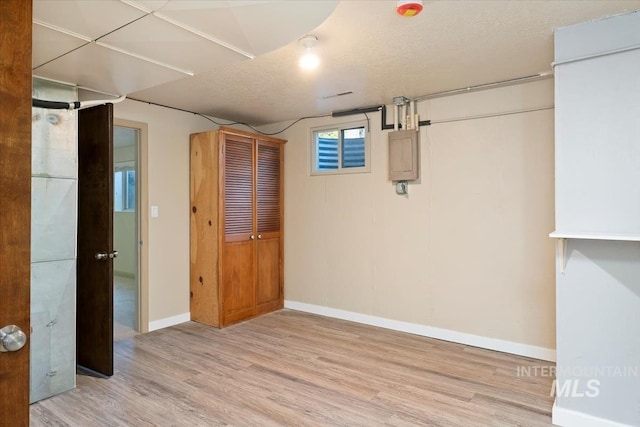 basement with baseboards, a textured ceiling, and wood finished floors