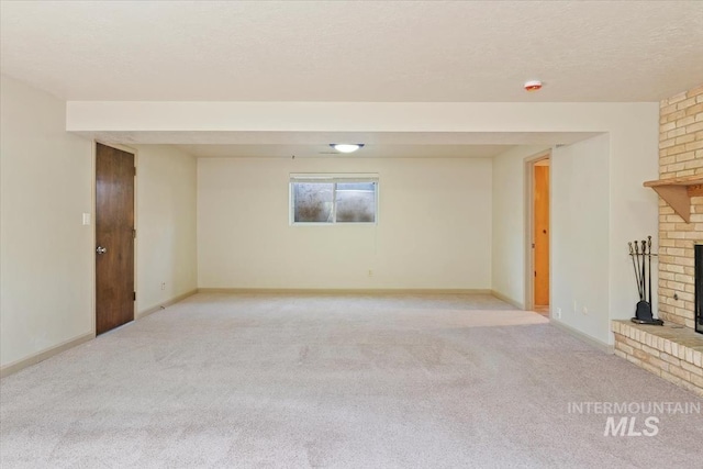 unfurnished living room with baseboards, light carpet, a textured ceiling, and a brick fireplace