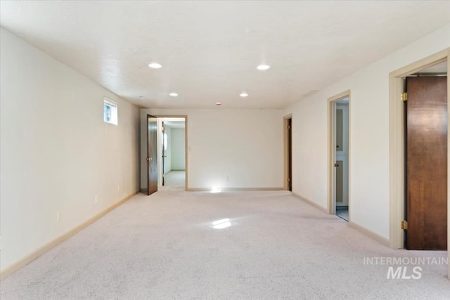 spare room featuring light carpet, recessed lighting, and baseboards