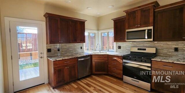 kitchen featuring stainless steel appliances, plenty of natural light, decorative backsplash, and light hardwood / wood-style flooring