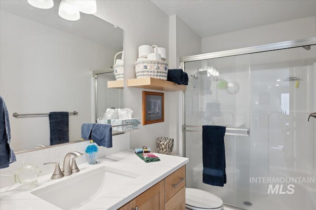 403 Antonette Cir, Cascade, ID 83611 - bathroom featuring a stall shower, vanity, toilet, and decorative backsplash
