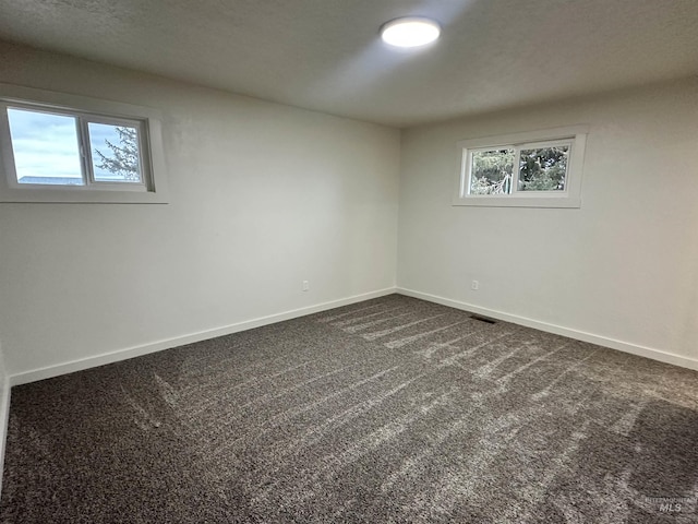 empty room with baseboards and dark carpet