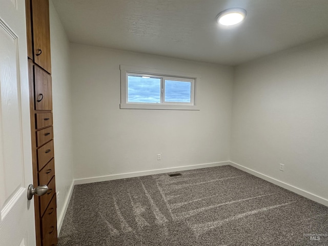 unfurnished bedroom with visible vents, baseboards, and dark carpet