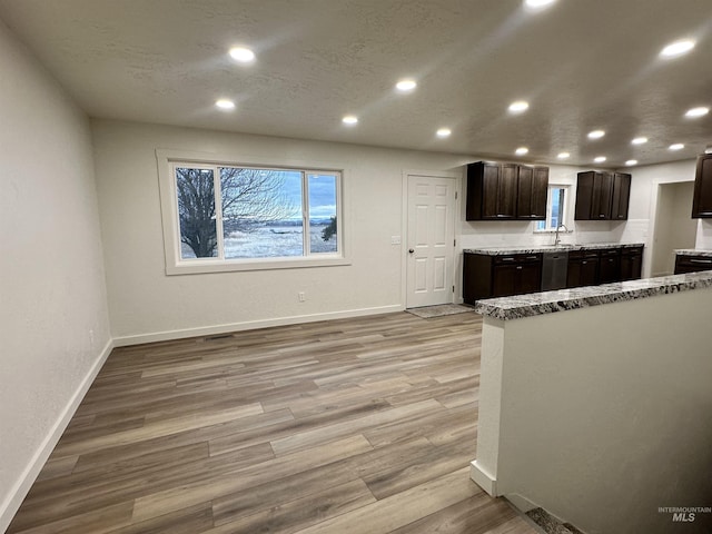 kitchen featuring dark brown cabinets, baseboards, dishwasher, and light wood-style flooring