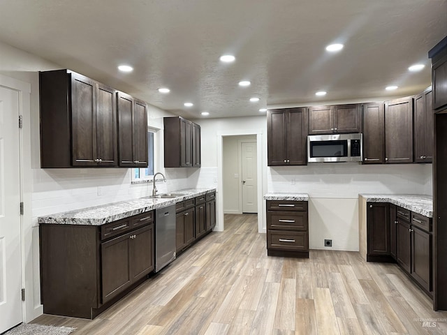 kitchen featuring dark brown cabinetry, decorative backsplash, appliances with stainless steel finishes, and light wood-type flooring