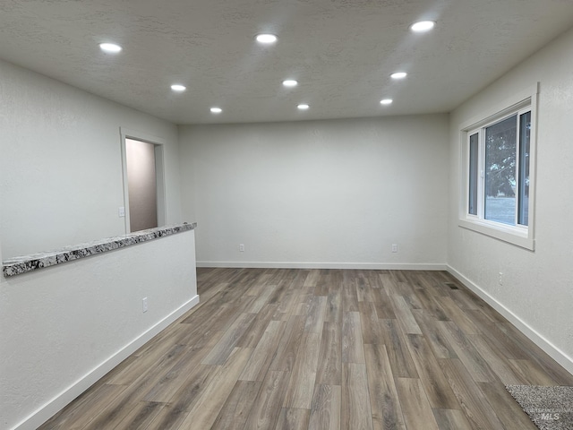 spare room featuring wood finished floors, recessed lighting, and baseboards