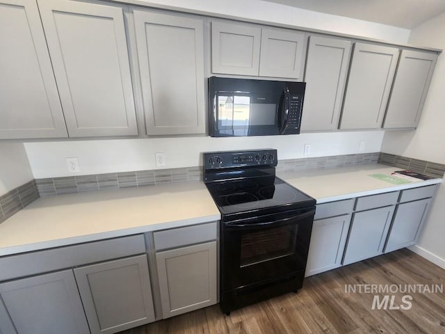 kitchen with black appliances, dark hardwood / wood-style floors, and gray cabinetry