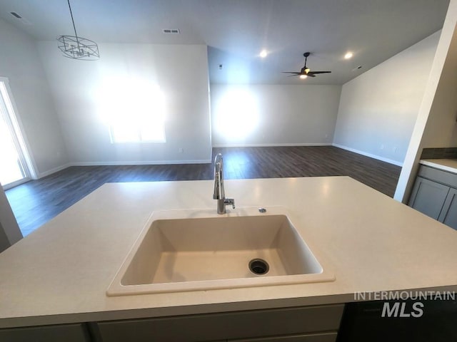 kitchen with pendant lighting, dark wood-type flooring, ceiling fan with notable chandelier, sink, and gray cabinets