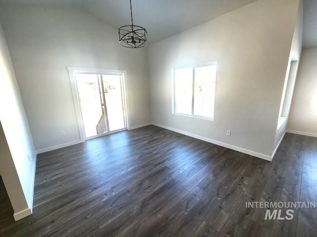 empty room with plenty of natural light, dark wood-type flooring, and a notable chandelier