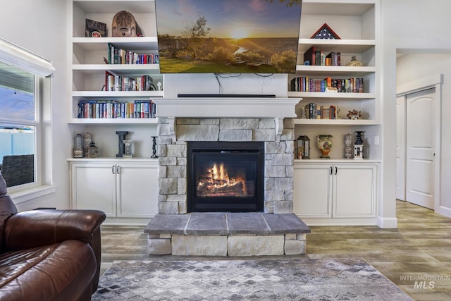 living area featuring wood finished floors, a fireplace, and built in features