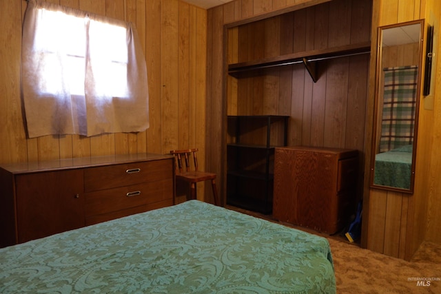 carpeted bedroom featuring a closet and wood walls