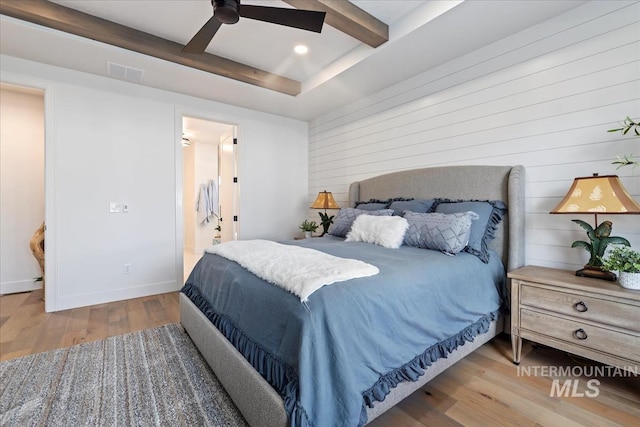 bedroom with beam ceiling, visible vents, ceiling fan, wood finished floors, and baseboards