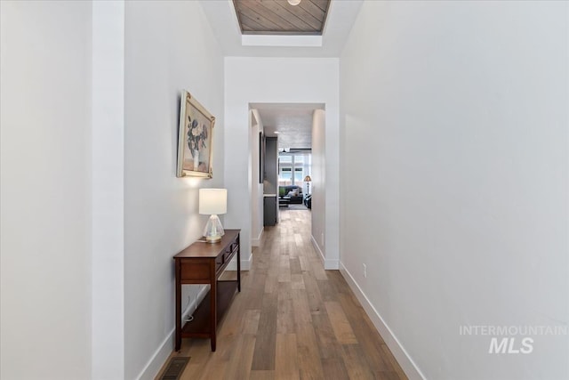 corridor with wood finished floors, visible vents, and baseboards