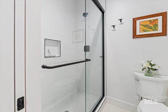 bathroom featuring a shower stall, toilet, and baseboards