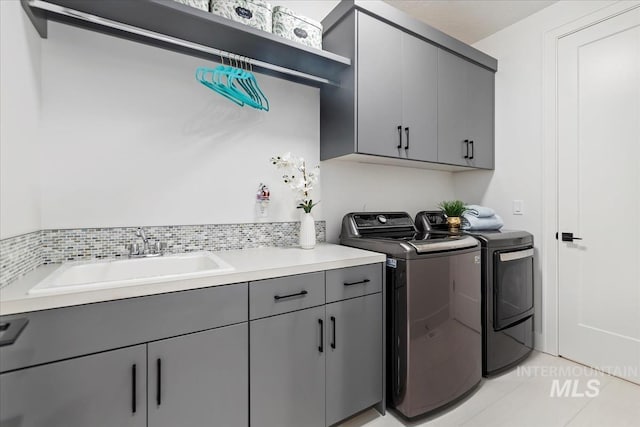 clothes washing area featuring cabinet space, a sink, washer and clothes dryer, and light tile patterned floors