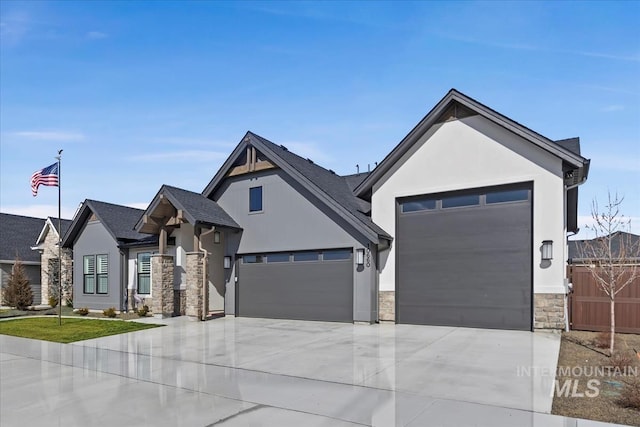 view of front of property featuring a garage, fence, stone siding, concrete driveway, and stucco siding