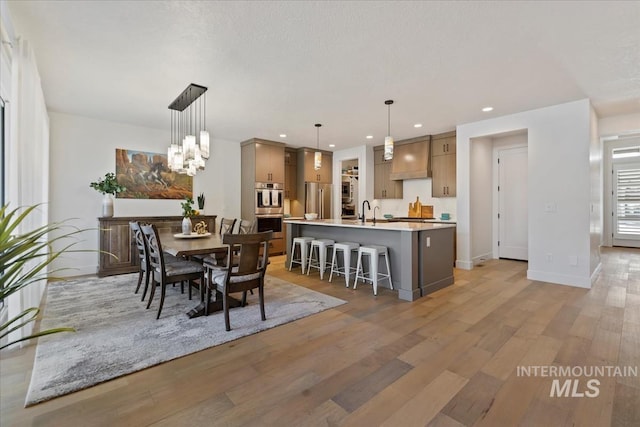 dining space with light wood finished floors, baseboards, a notable chandelier, and recessed lighting