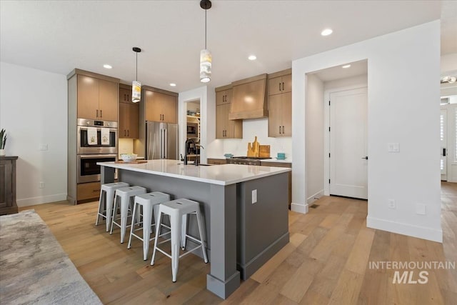 kitchen with premium range hood, a breakfast bar area, stainless steel appliances, and light wood-style flooring