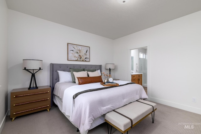 carpeted bedroom featuring baseboards and ensuite bathroom