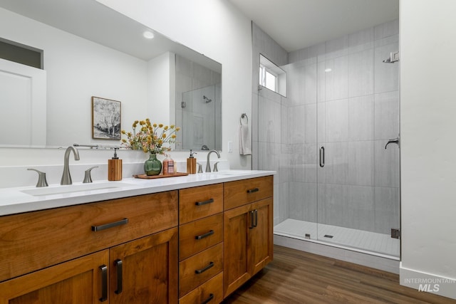 bathroom with double vanity, a shower stall, wood finished floors, and a sink